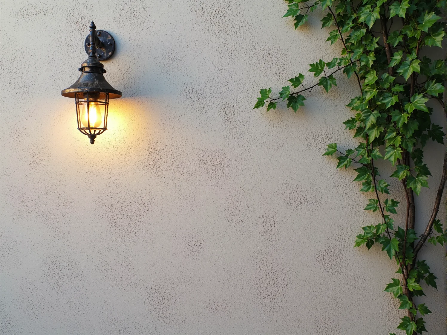 Kinkiet zewnętrzny z kutego żelaza, idealny do oświetlenia wejścia w stylu śródziemnomorskim.